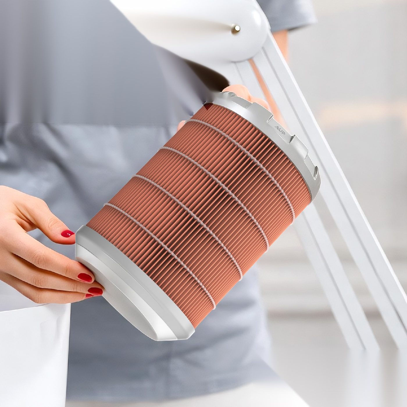 Une technicienne en pose d'ongles tenant un filtre à cartouche PureFibe à côté du bras d'un aspirateur pour ongles